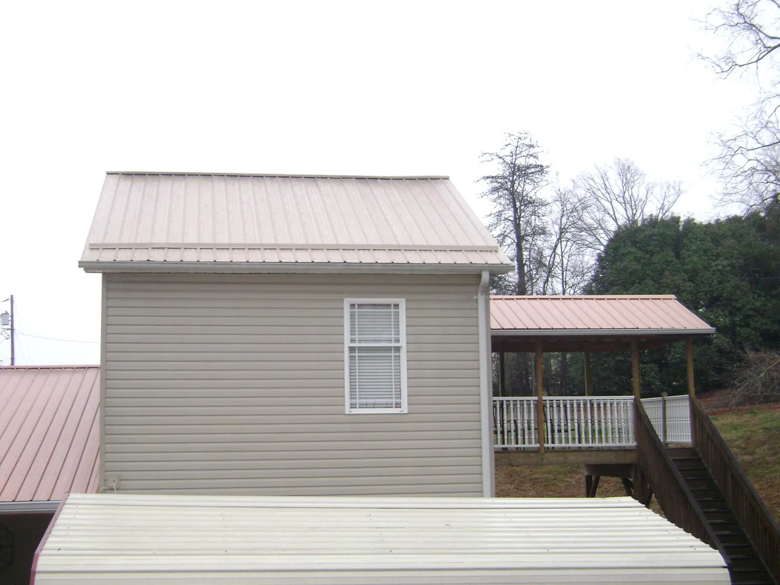 Tan metal roofs on a two story addition and attached porch, from a Roof Replacement job in Venice